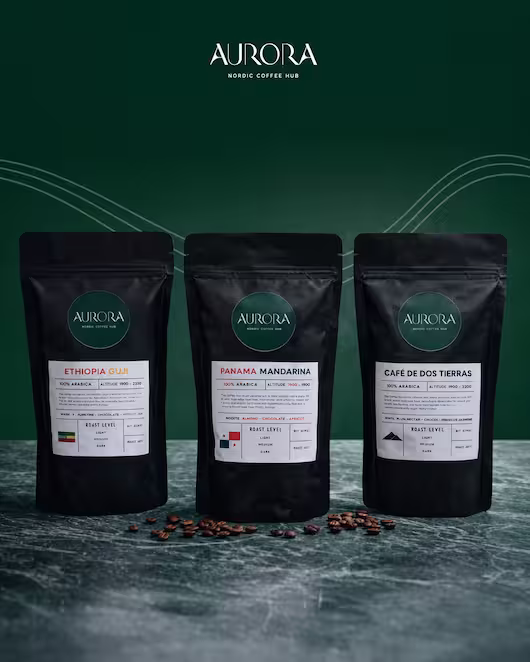 Three black bags of Aurora Nordic Coffee Hub specialty beans—Ethiopia Guji, Panama Mandarina, and Café de Dos Tierras—displayed on a marble surface against a dark green background.
