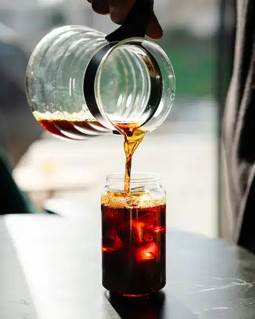 Freshly brewed V60 pour-over coffee being poured into a ceramic cup at Aurora Coffee Hub.