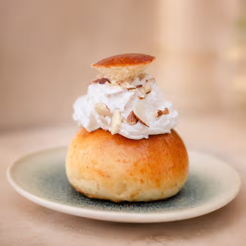 A traditional Swedish Semla cardamom bun filled with almond paste and whipped cream at Aurora Coffee Hub.
